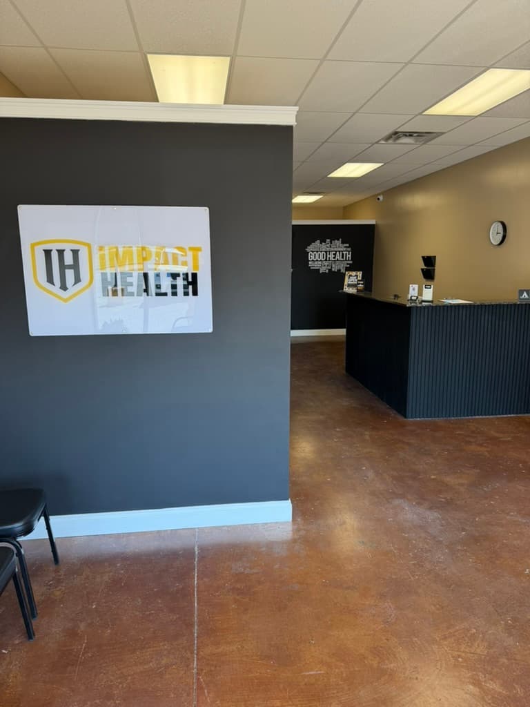 Impact Health Corinth lobby, framed Impact Health sign on charcoal wall, reception desk and GOOD HEALTH wall art beyond