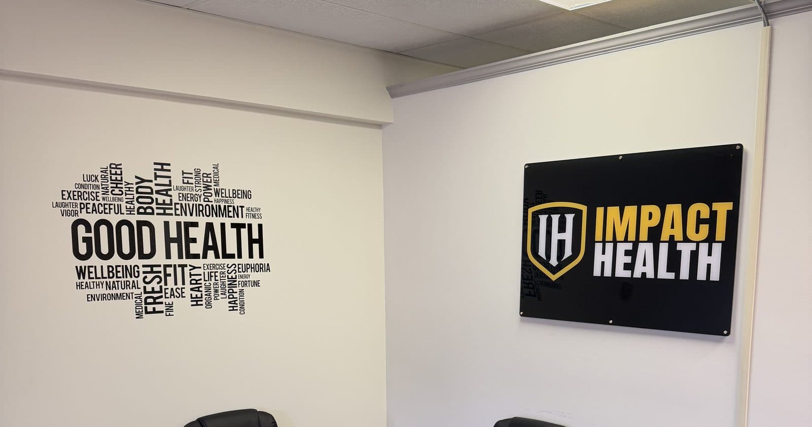 Inside the Impact Health Tupelo clinic with the Good Health word-art wall and the Impact Health sign