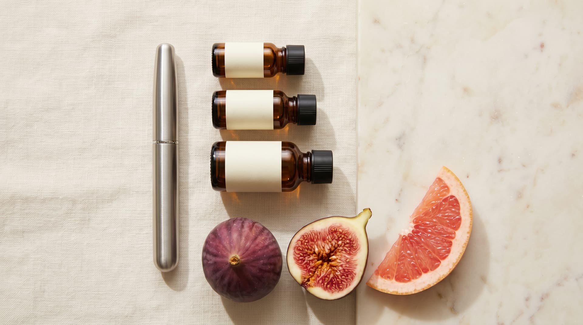 Three amber GLP-1 vials with fresh fig and grapefruit on cream linen